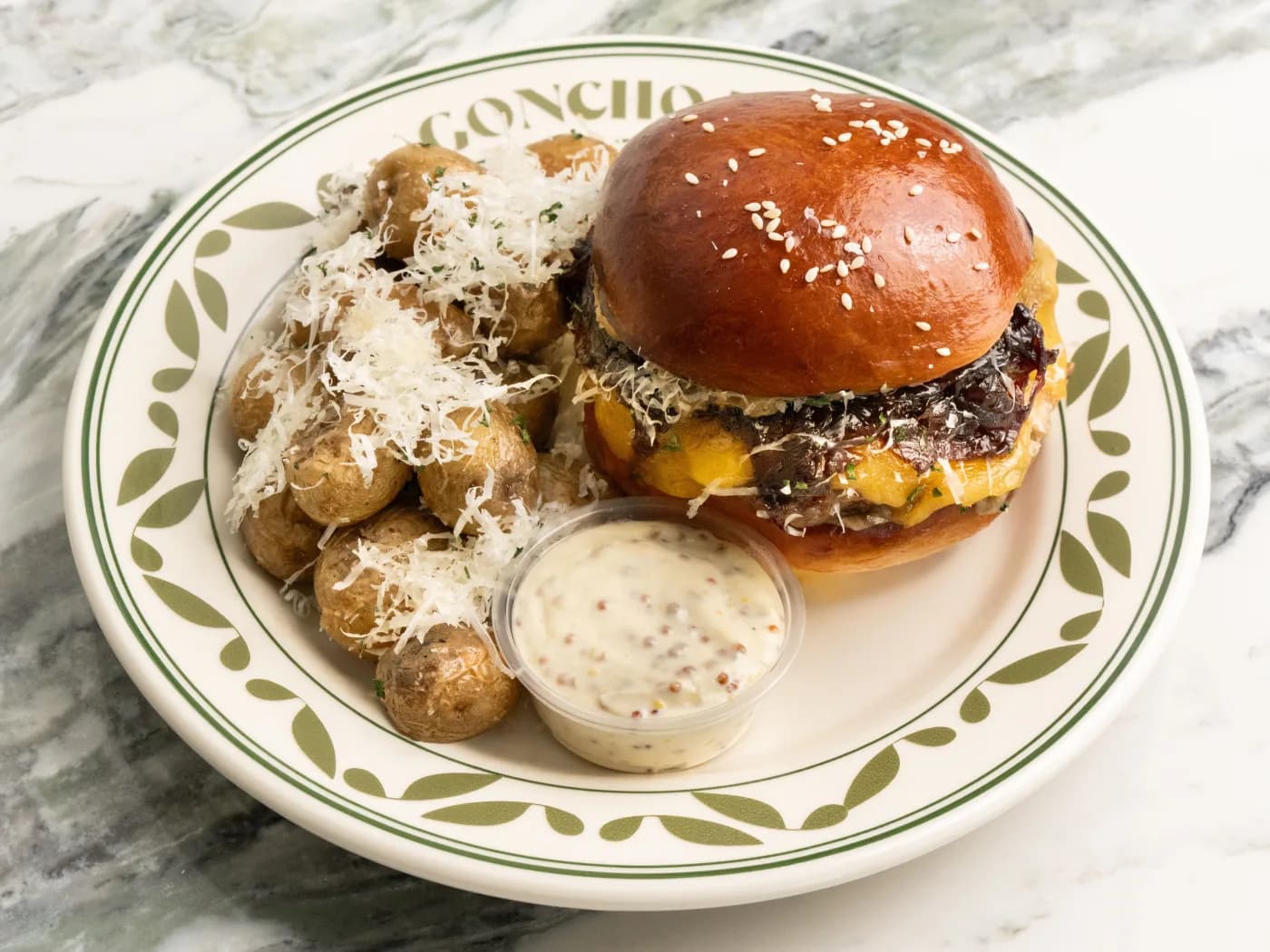 GONCHO burger with golden baby potatoes and house dip on a branded plate